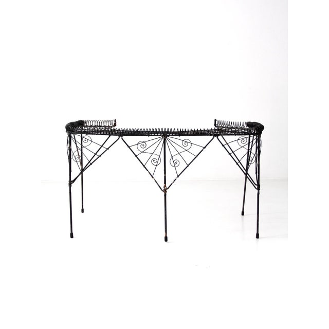 This Victorian-era plant stand, dating from the mid to late 19th century, features a striking black demilune wire frame...