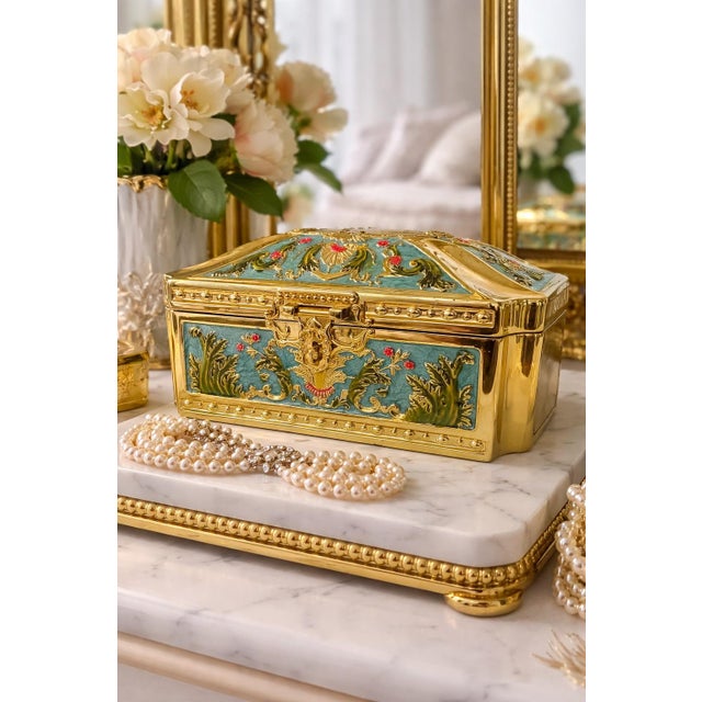 This striking Hollywood Regency jewelry casket features an ornate gilt metal body beautifully accented with textured...