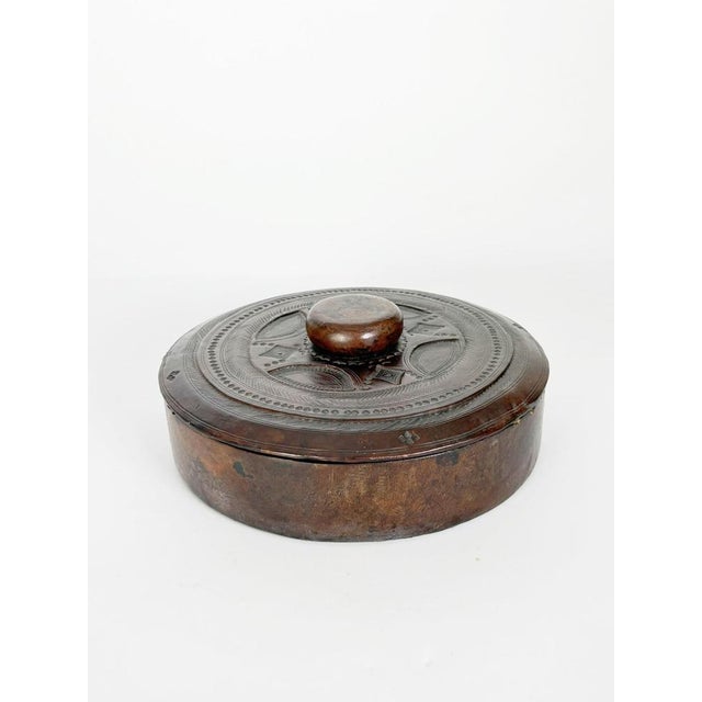Decorative round leather box featuring an embossed geometric motif on the lid and a rich dark brown patina acquired over...
