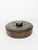 Decorative round leather box featuring an embossed geometric motif on the lid and a rich dark brown patina acquired over...