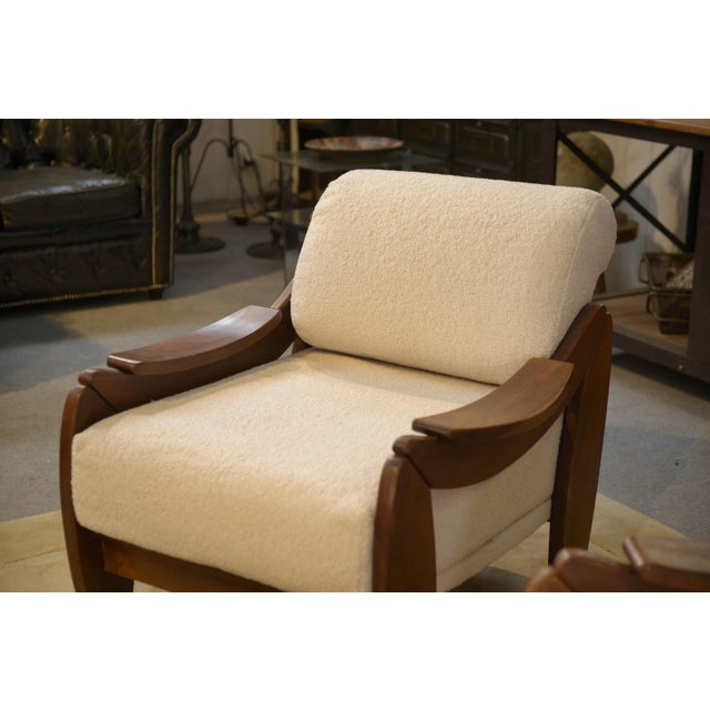 Pair of Brutalist armchairs from the 1970s, with thick, rounded wooden frames. The armrests are sculpted in the shape of...