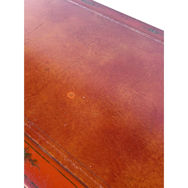 A ladies Desk in the chinoiserie style. French style cabriole legs and a leather top. A red / oxblood finish decorated in...