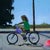 Traces by Emma Kalff | Oil on panel Girl riding a purple bicycle on a sunny street. For Sale