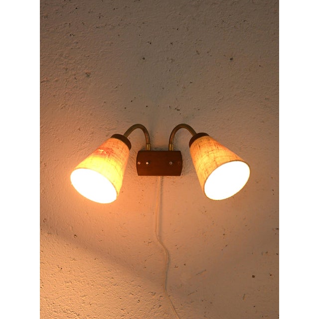 Vintage Scandinavian lamp with two conical lampshades in light fabric and adjustable golden arm. The lampshades are made...