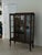 Elegant antique glass display cabinet featuring a rich, dark mahogany wood frame, graceful cabriole-style legs on casters,...