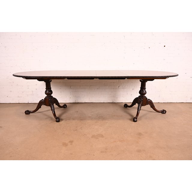 An exceptional antique Georgian or Chippendale style double pedestal extension dining table In the manner of Baker...