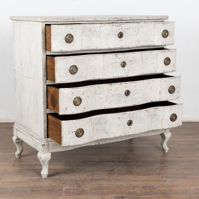 The antique white painted finish is captivating in this attractive large chest of four drawers resting on curved cabriole...