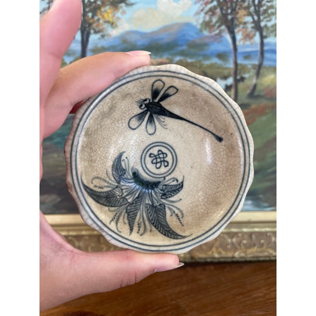 A small vintage Vietnamese ceramic tea bowl featuring hand-painted cobalt blue decoration on a cream crackle-glazed...