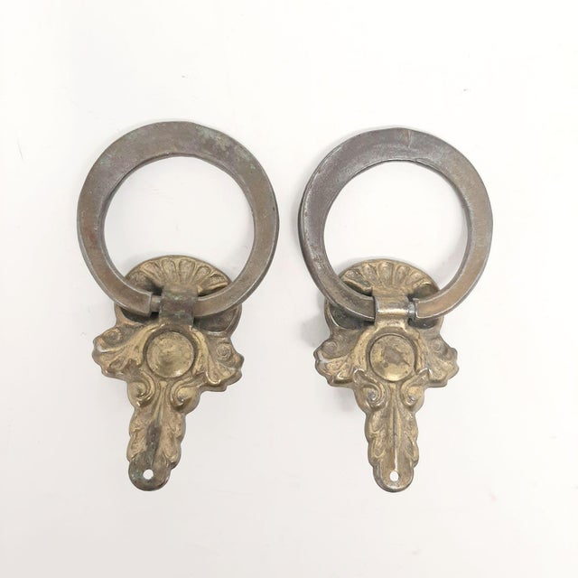 This pair of ring knobs are key shape and were used as furniture hardware. They are gold colored handles on a dresser,...