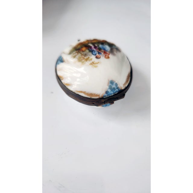 A refined antique French Limoges porcelain trinket box, modeled in the form of a shell and exquisitely hand-painted with a...