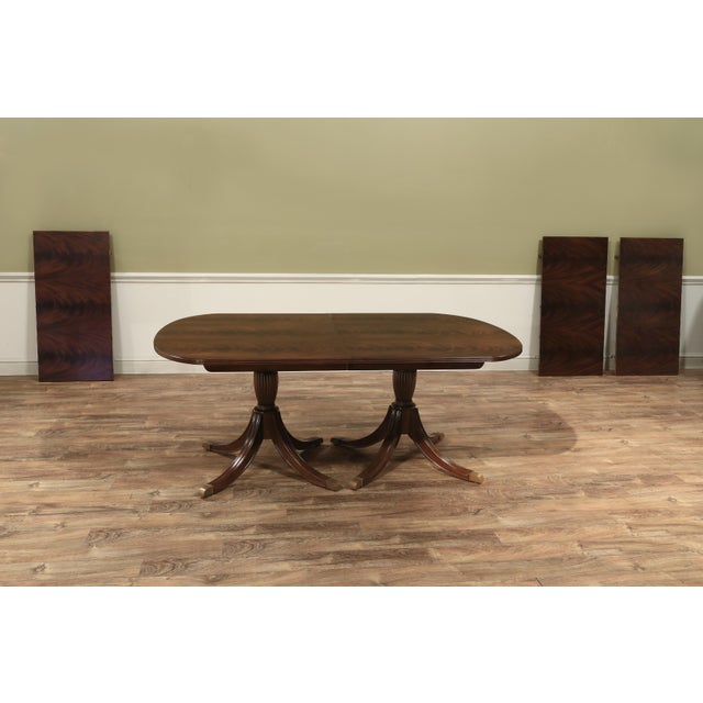 An exclusive double pedestal mahogany dining room table made by AntiquePurveyor for seating up to 14 people. It has an...
