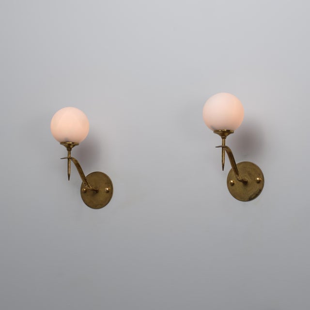 Pair of italian wall sconces dating from the 1950s, designed with a refined brass structure and spherical opaline glass...
