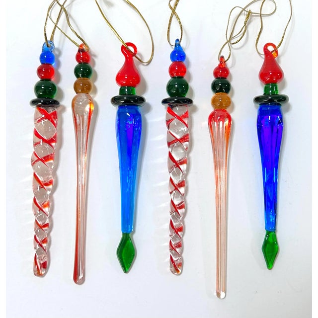 Set of six large vintage handblown glass icicle ornaments featuring elongated clear and jewel-tone glass bodies with bold...