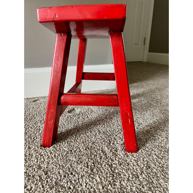 The stool is a Chinese red-lacquered hardwood stool/bench, with curved seat and mortise-and-tenon joinery, mid-20th...