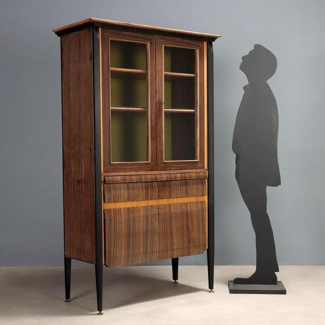 Elegant vintage piece with laminate inserts, exotic wood veneer, and stained wood legs with brass tips. It features hinged...