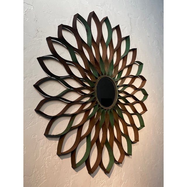 A beautiful decorative fornasetti style weathered metal star-burst with center circular mirror wall hanging, offering...