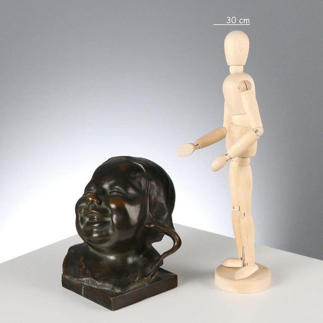 Bronze sculpture depicting the head of a laughing child. Square marble base. Artist: Anonymous. This piece is attributed...