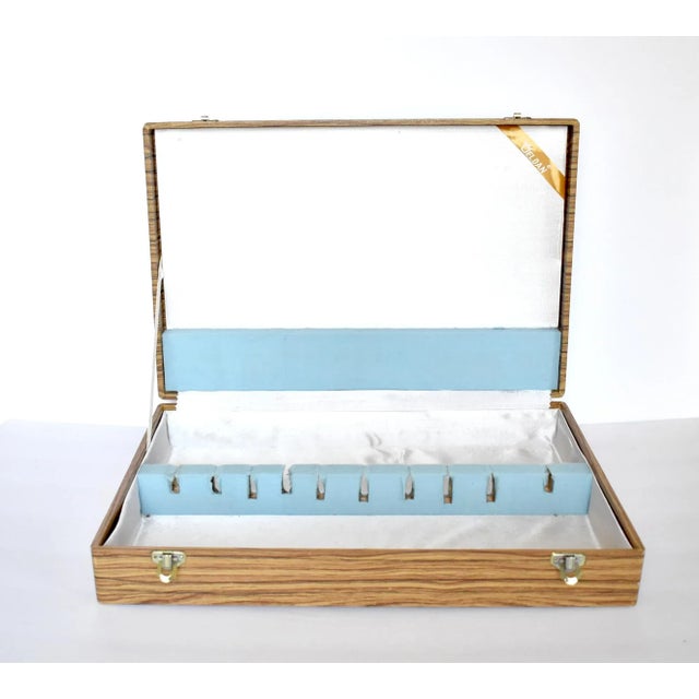 A vintage, mid-century silverware storage box with a faux wood pattern, and a white fabric and blue felted fabric interior...