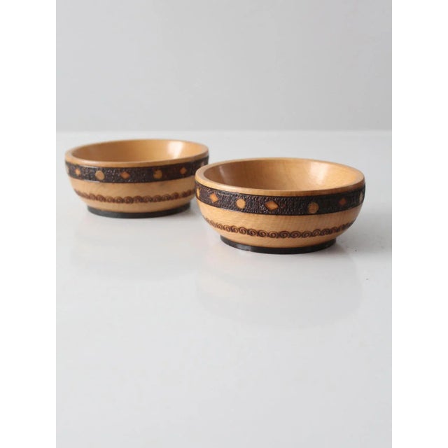This is pair of vintage wooden bowls. The decorative bowls feature hand-tooled pyrography in a geometric pattern.