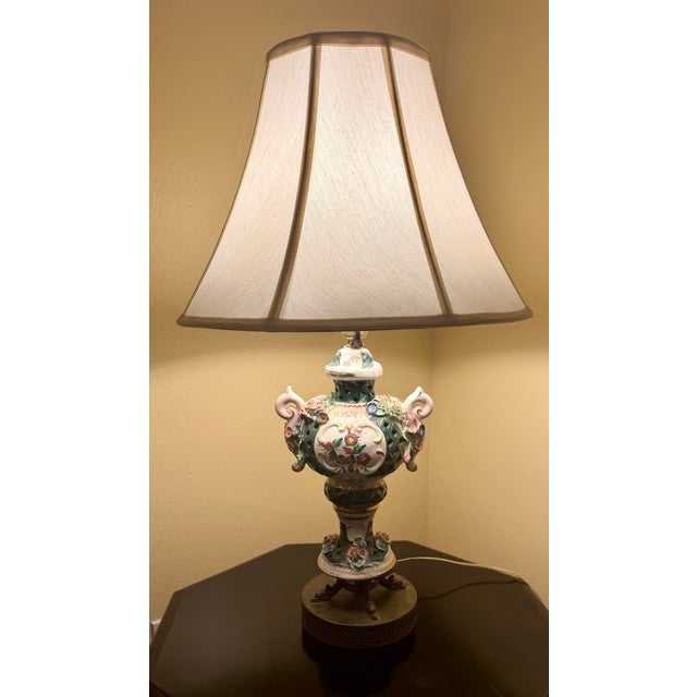 A charming pair of vintage porcelain table lamps featuring richly detailed hand-applied floral decoration, reticulated...