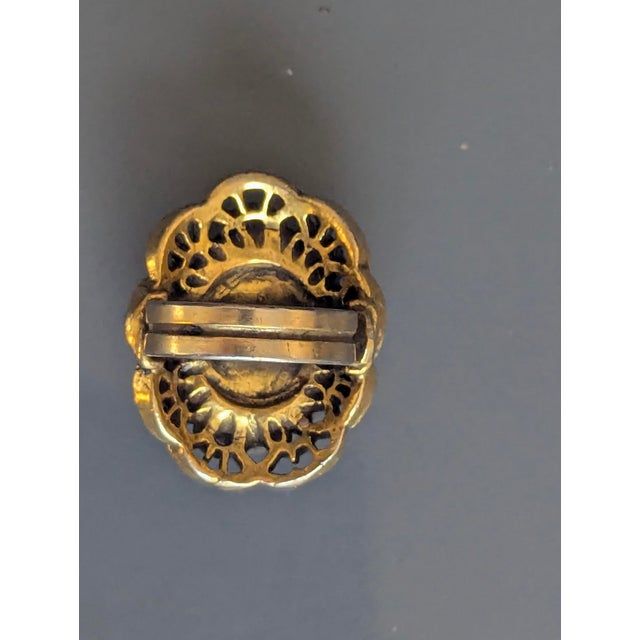 Brass cameo carved shell chiseled came encased in brass. The band is adjustable medium to large.