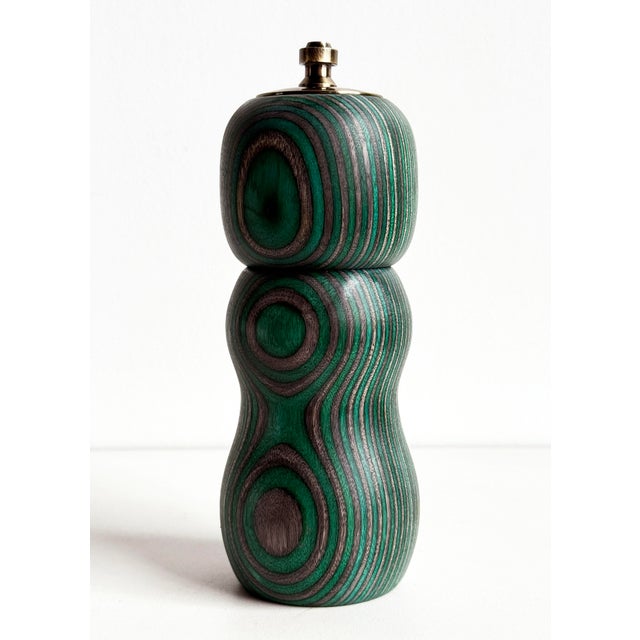 A striking modern artisanal pepper mill crafted from dyed laminated birch with a sculptural turned form and bold...