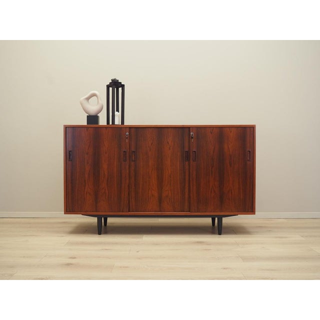 The dresser was made in the 1970s, Danish production. The structure is covered with rosewood veneer. The legs are made of...