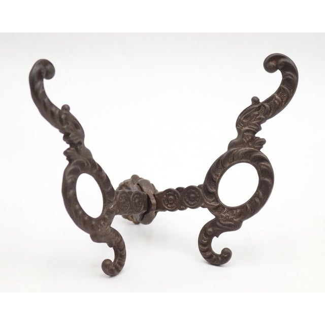 Neoclassical style hall tree hook made of cast iron with a black finish. There is a screw attached to the back with a nut...
