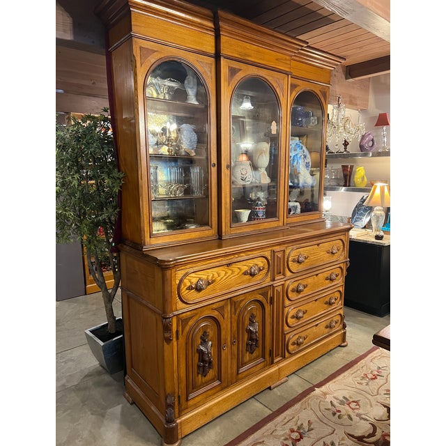 A substantial American Jacobean Revival oak china cabinet and sideboard, circa 1925–1935, executed in richly grained...