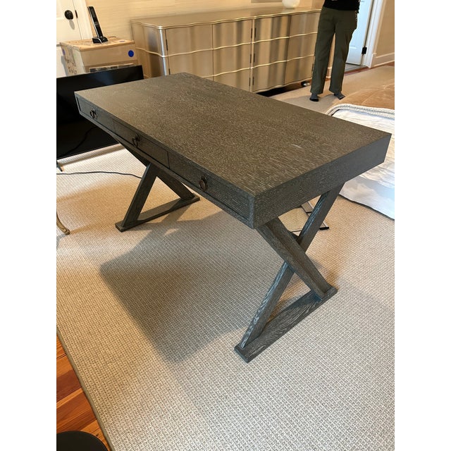 Stylish sleek cerused wood writing desk having a dark grey color and campaign style X motif in the base. Single drawer and...