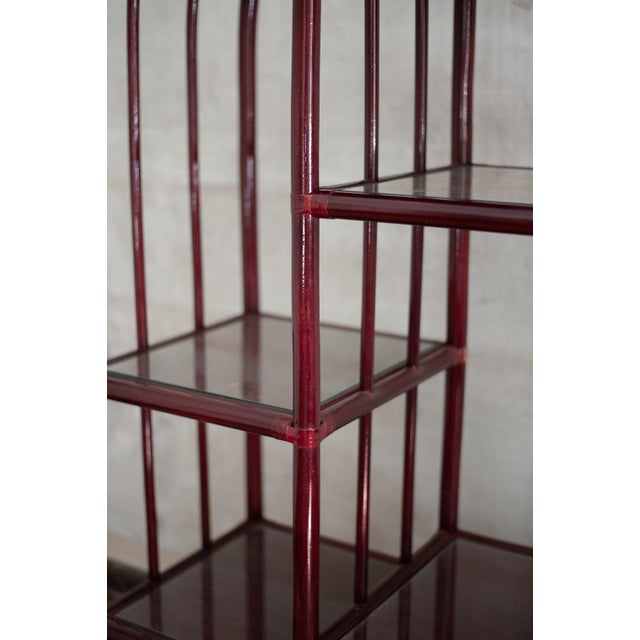 Lacquered arch Bookcase – 1980s Made of red lacquered bamboo with smoked glass shelves and rush bindings. The lower...