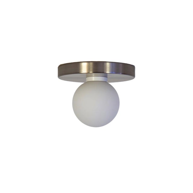 Minimal from top to bottom. This black flush mount pairs a metal base with a soft glass globe. Cool, calm, and quietly...