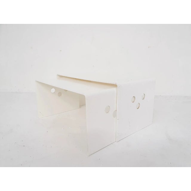 White plastic nesting tables. Some traces of use and a small dent in the larger one.