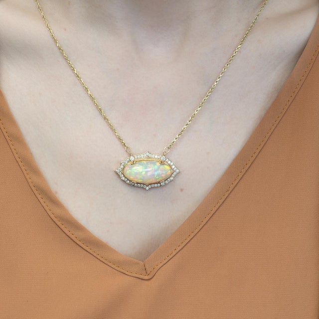 A luminous 11.2 ct natural opal glows with shifting fire, framed by sparkling natural diamond accents. Crafted in solid...