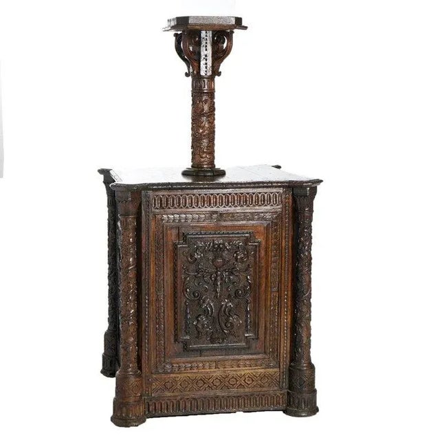 An early antique Continental reliquary cabinet offers deeply carved oak construction with central foliate column having...