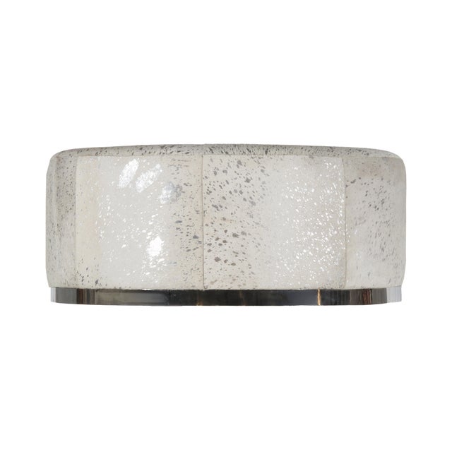 A statement of modern luxury, this large round ottoman is upholstered in natural cowhide adorned withelegant foil accents...