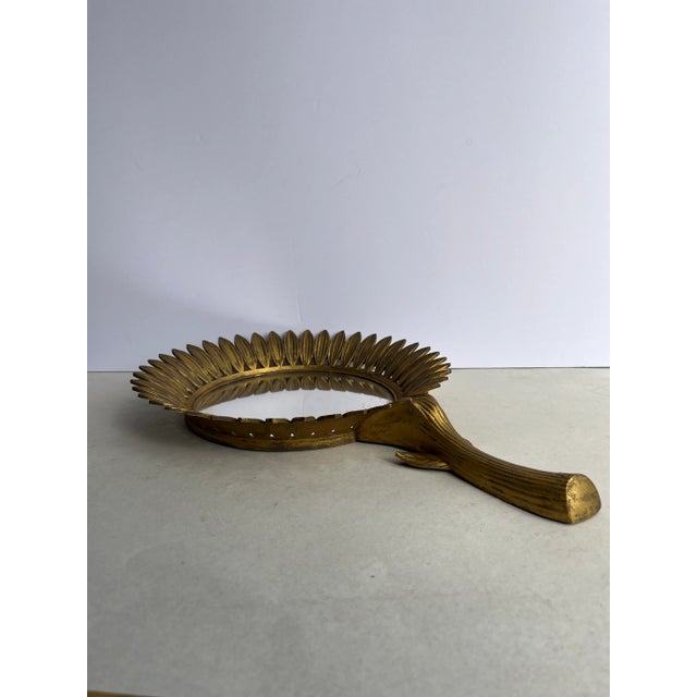 A single sunflower shaped wall mirror with gold finish.