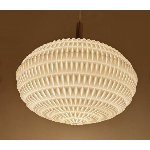 Mid century vintage pendant light with a flattened composite acrylic globe shade with diamond relief patterns and brass...