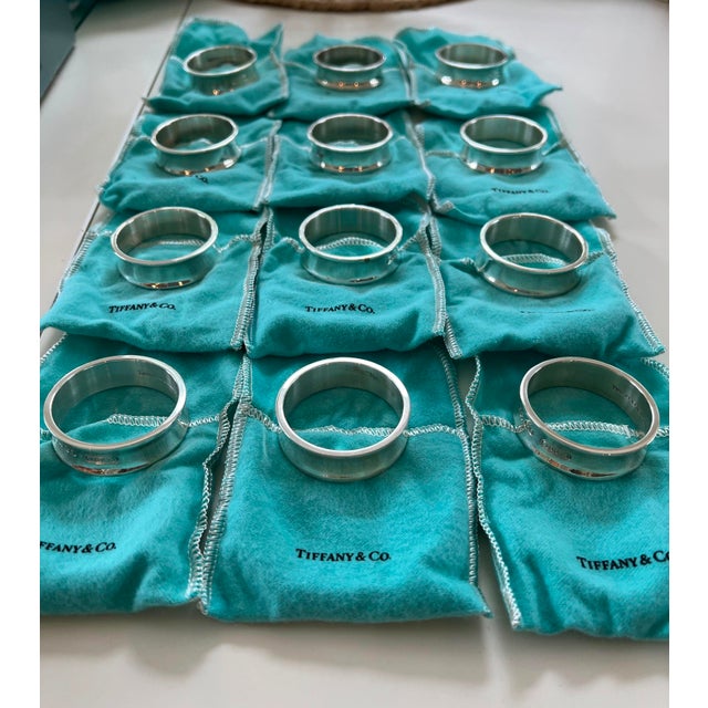 This fine set of 12 authentic Tiffany & Co. napkin rings is crafted from high-polished sterling silver, featuring a...