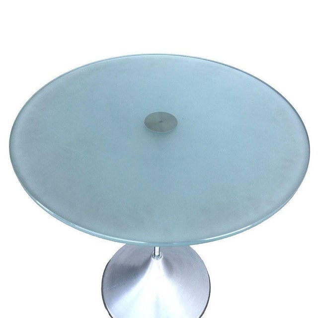 Y2K era side table featuring a floating frosted green glass top resting on a brushed aluminum base. The table echoes the...