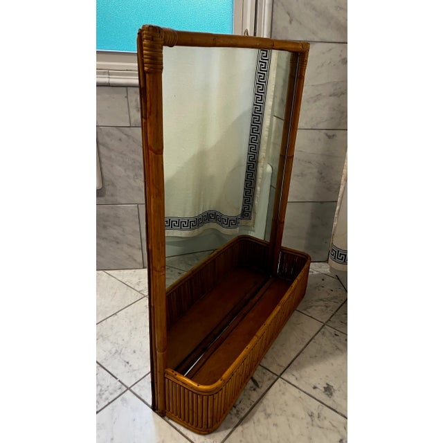 MCM rattan wall mirror with a pocket that can be used as a planter. Rattan pieces are joined together with wicker...