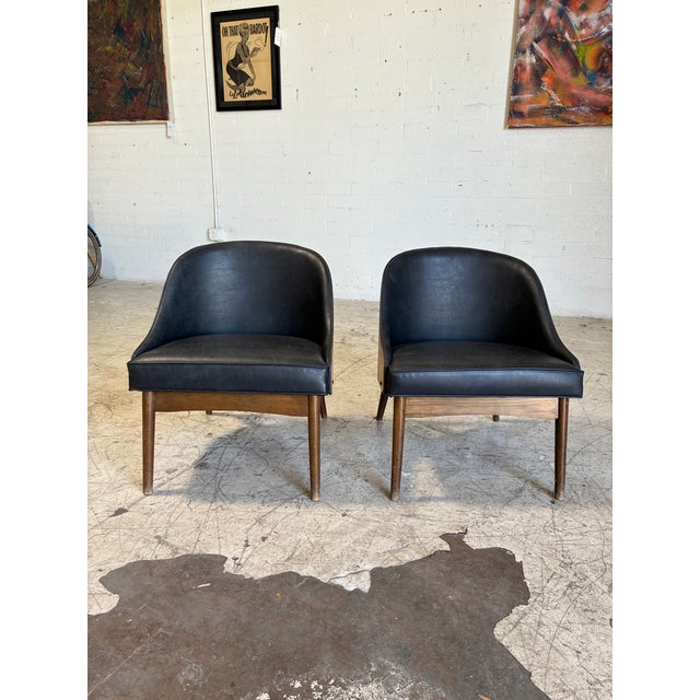 Mid century modern lounge chairs by Kodawood, featuring molded walnut frames, tapered legs and black vinyl seats and back....