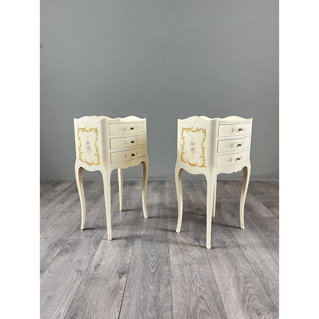 Charming pair of Louis XV style bedside tables in cream lacquered wood with painted decoration. Each table is adorned with...