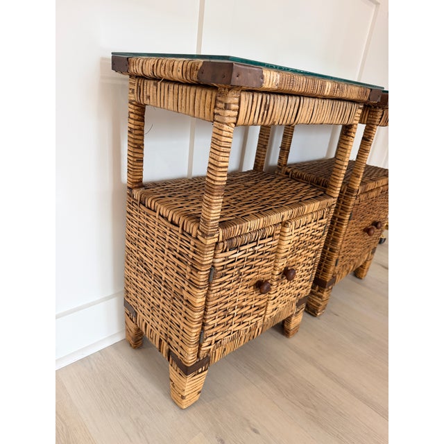 Pair of vintage rattan nightstands featuring custom glass tops, open shelving, and lower cabinet storage with charming...
