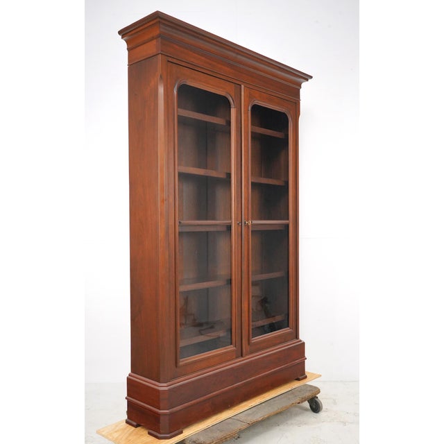 Traditional style double door walnut bookcase cabinet with five adjustable wood shelves enclosed. This features the...