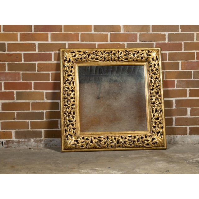 An Italian giltwood square-shaped mirror from the mid 20th century with openwork carved foliage and acanthus leaves...