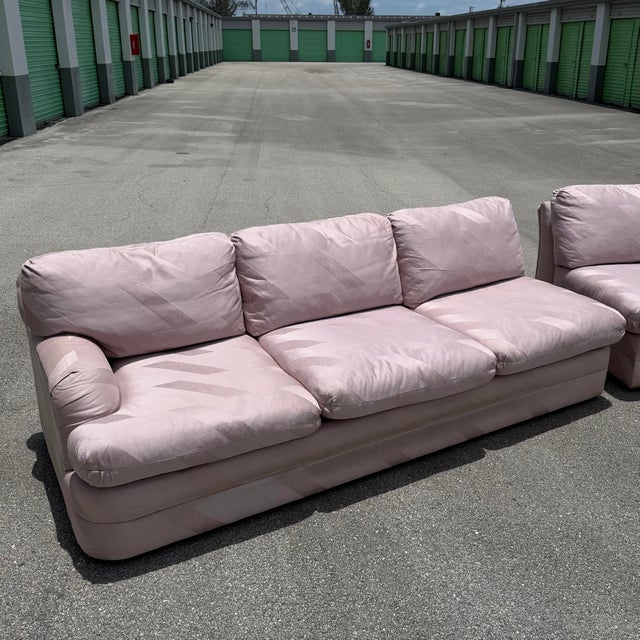 A striking Postmodern sectional sofa set consisting of two matching pieces upholstered in a soft mauve-pink geometric...