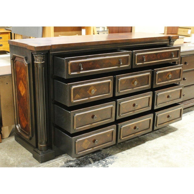 This piece features a rich two‑tone wood finish with a polished top and a symmetrical layout of eleven drawers. Each...