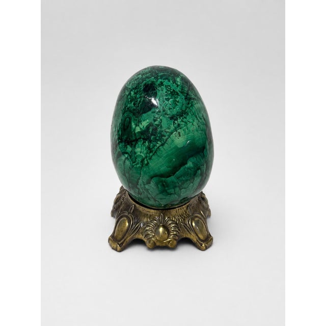 A striking polished solid malachite egg, notable for its substantial weight, deep emerald-green color, and richly figured...
