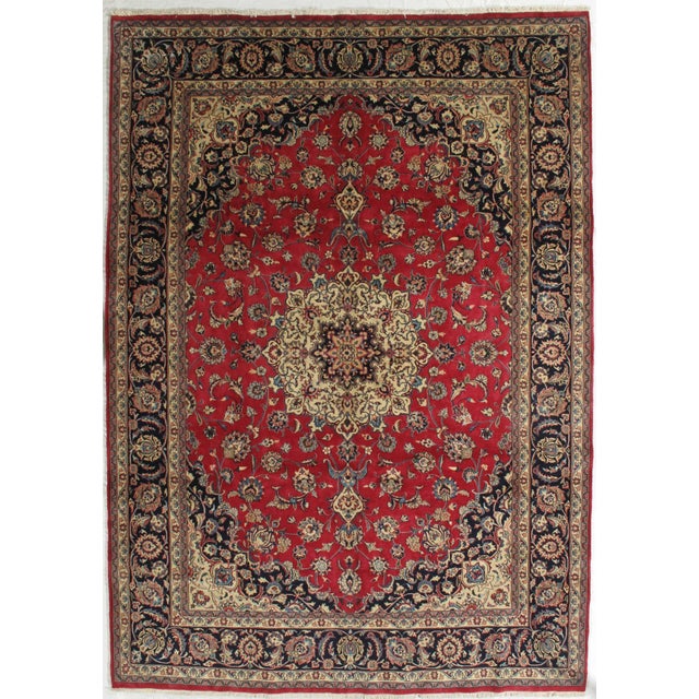 Antique hand-knotted Persian Mashad wool rug with a red field featuring a central medallion and dense floral motifs,...
